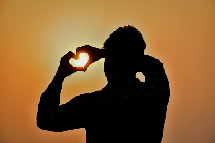 Silhouette Of Person Making Heart Shape With Hands 