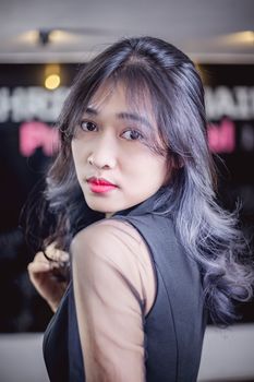 Young woman posing in a black blouse with mesh sleeves, looking over shoulder. - Fotografer Sidoarjo