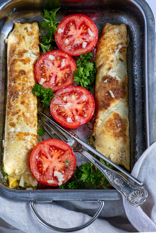 Free Delicious baked crepes with fresh tomato slices and herbs on a tray, perfect for a hearty meal. Stock Photo