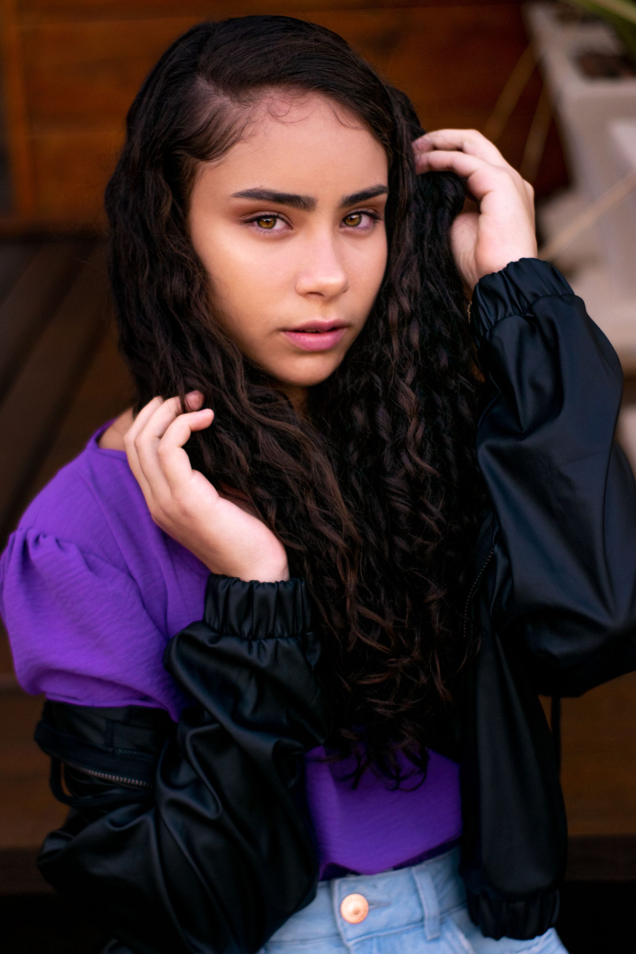 Stylish portrait of a young woman in Pedra Azul, Brazil with curly hair and vibrant clothing.