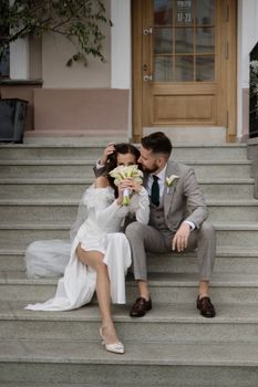 Bride and groom sitting on steps embracing, showcasing wedding attire.