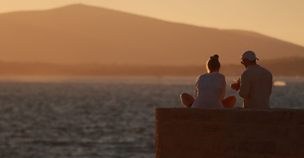 A couple watching the sun set over the shore at Alghero in Sardinia