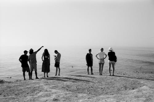 Grayscale Photo of People Standing on Shore