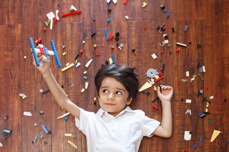 Interested Kid Playing With Handmade Plane On Floor