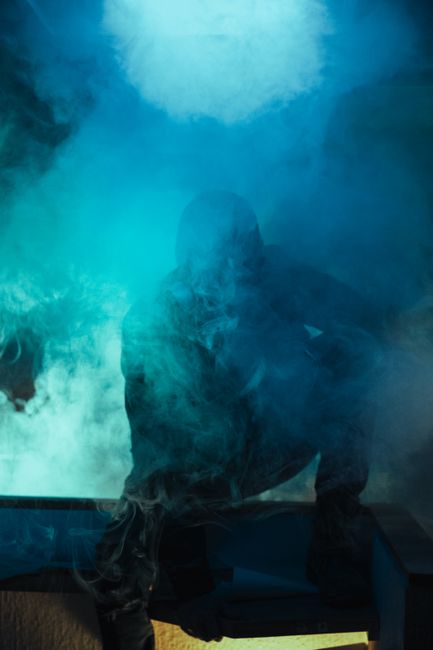Fotomural Silueta intrigante de una persona envuelta en humo azul, creando un ambiente inquietante y místico.