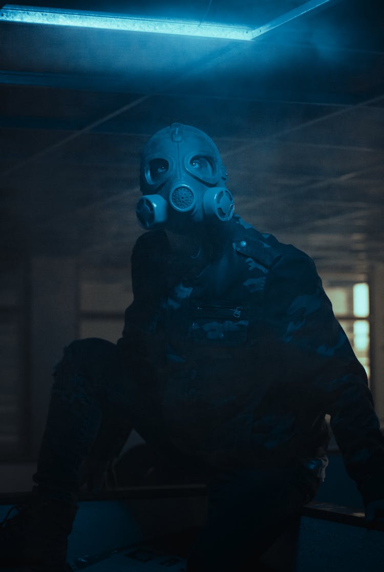 Man In Gas Mask Crouching On Floor Of Room