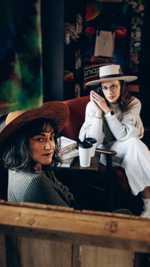 Free Two fashionable women enjoying coffee in a cozy café in Turkey, wearing wide-brim hats. Stock Photo
