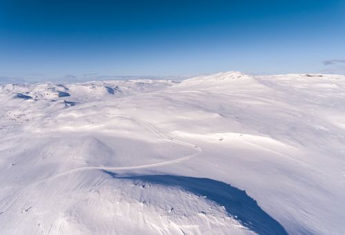 Free High-altitude view showcasing Norway's serene, snow-covered mountain landscape under clear blue skies. Stock Photo