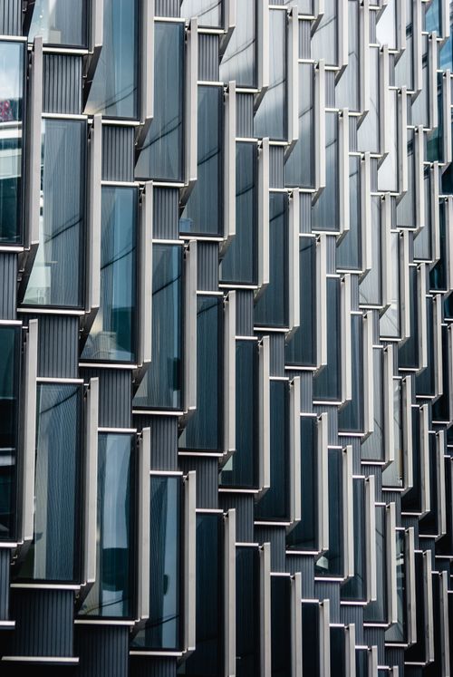 Free Close-up view of a modern glass and metal building facade showcasing unique geometric patterns in London. Stock Photo