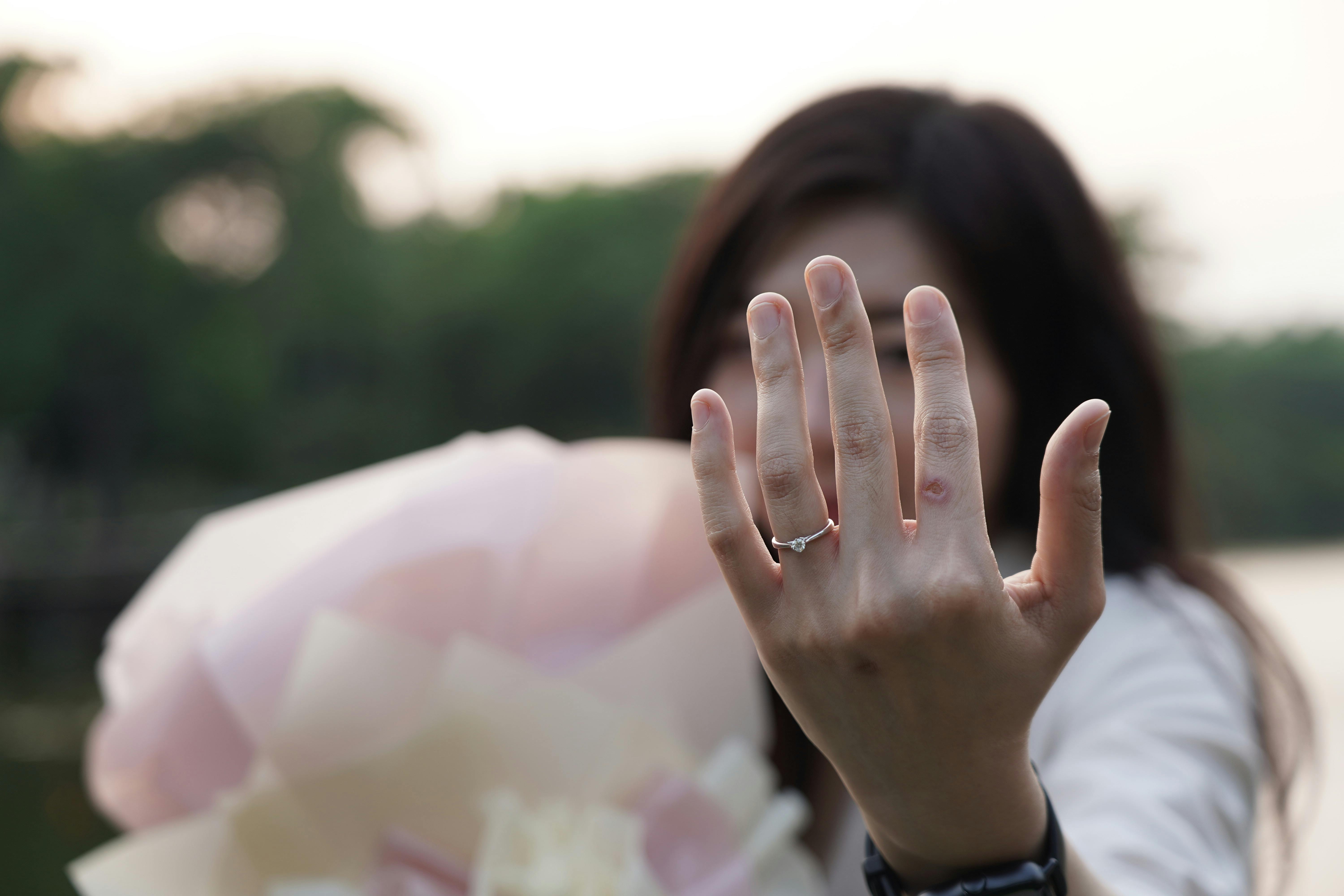 A woman displays her engagement ring in an outdoor setting, symbolizing love and commitment.