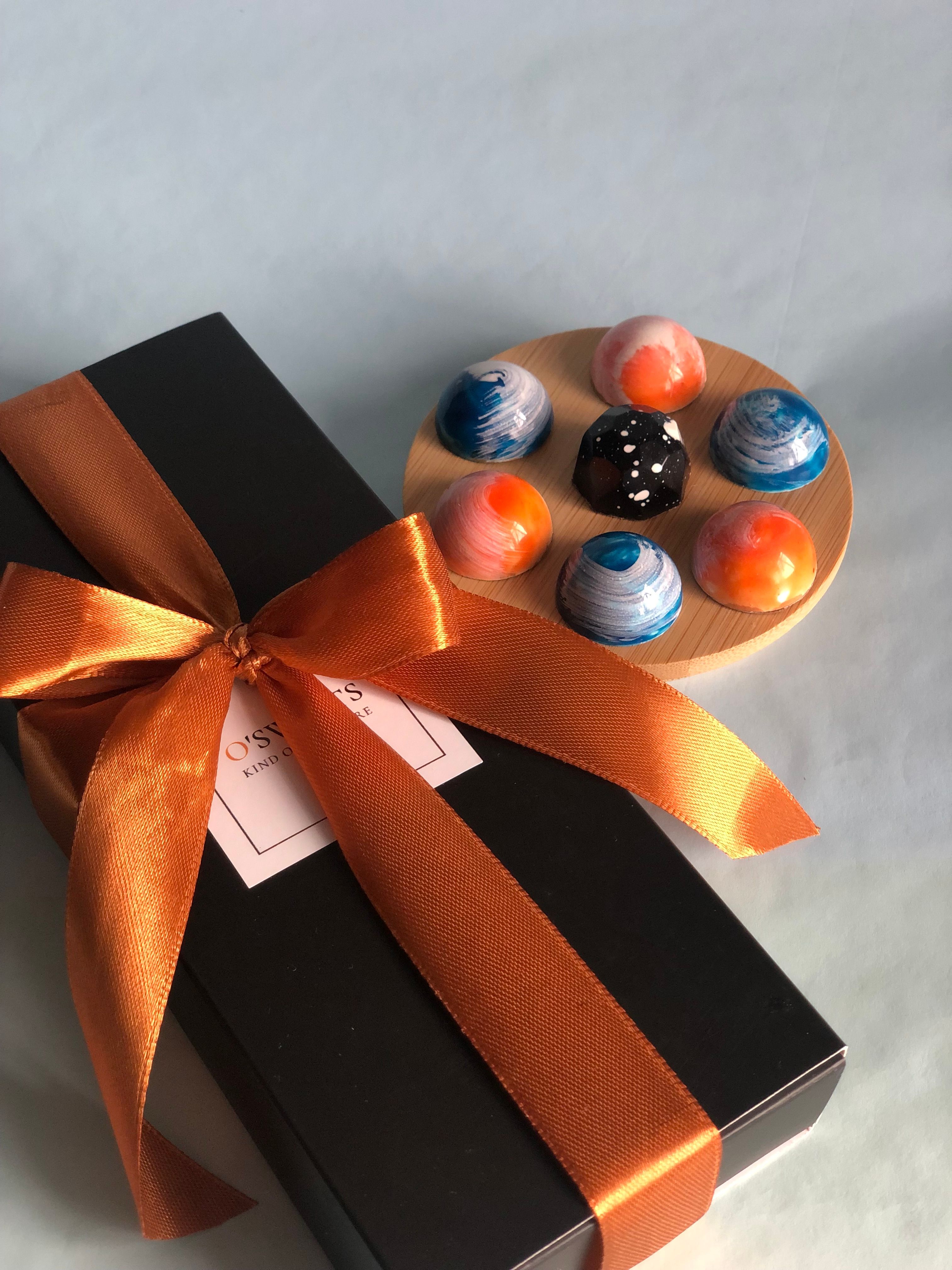 Dark chocolate truffles coated in cocoa powder and crushed pistachio, arranged in a gift box with ribbon
