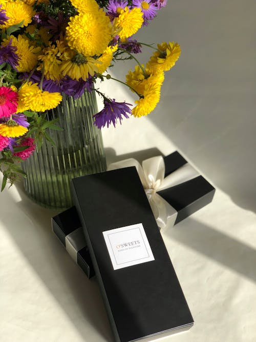 Flowers on Glass Vase and Black Gift Boxes 