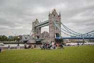 在伦敦的标志性塔桥旁，人们在阴天欣赏公园的景色