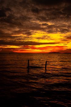 Vibrant ocean sunset featuring a dramatic cloudy sky in vivid orange hues.
