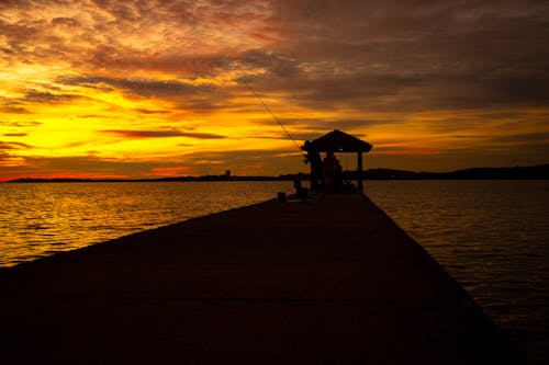 Silhouette of a Person Fishing on a Dock