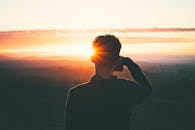 日出时分，一个人的剪影映衬着充满活力的天空和宁静的风景