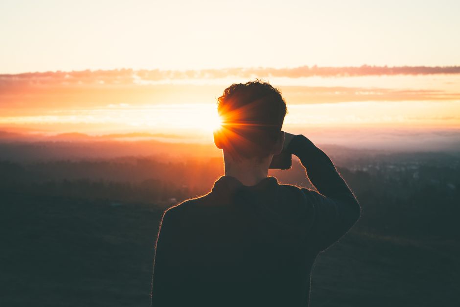 Silhouette of a man at sunrise, capturing the vibrant sky and serene landscape