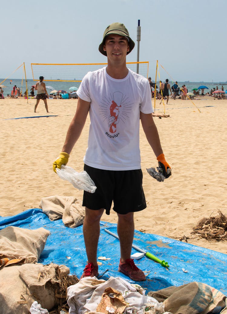 A Man In A White Shirt And A Bucket Hat Collecting Garbage