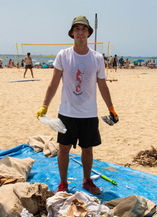 Free A dedicated young man participates in a beach cleanup in Barcelona, promoting environmental awareness. Stock Photo