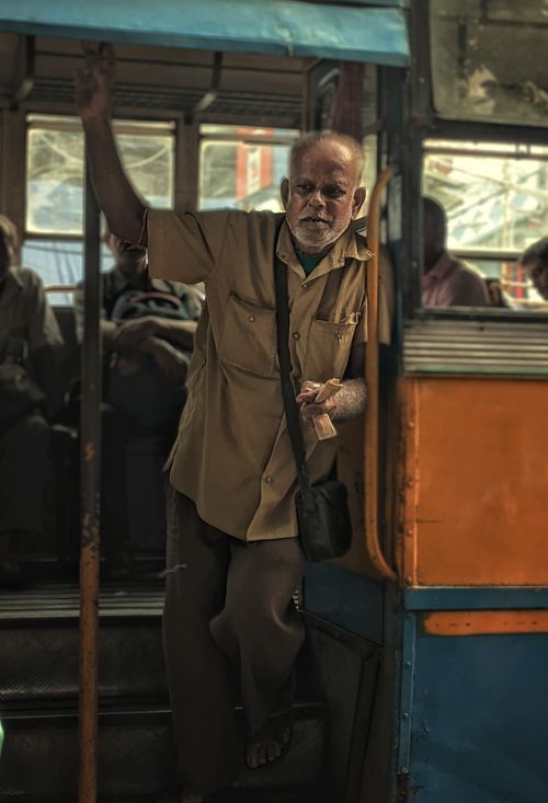 Free An elderly man working as a conductor on a classic public bus, engaging with passengers. Stock Photo