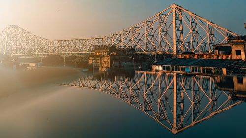 Free Stunning view of Howrah Bridge reflecting over calm water during sunset, Kolkata. Stock Photo