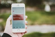 一个人拿着智能手机，屏幕上显示着一个能追踪步数和户外距离的健身应用