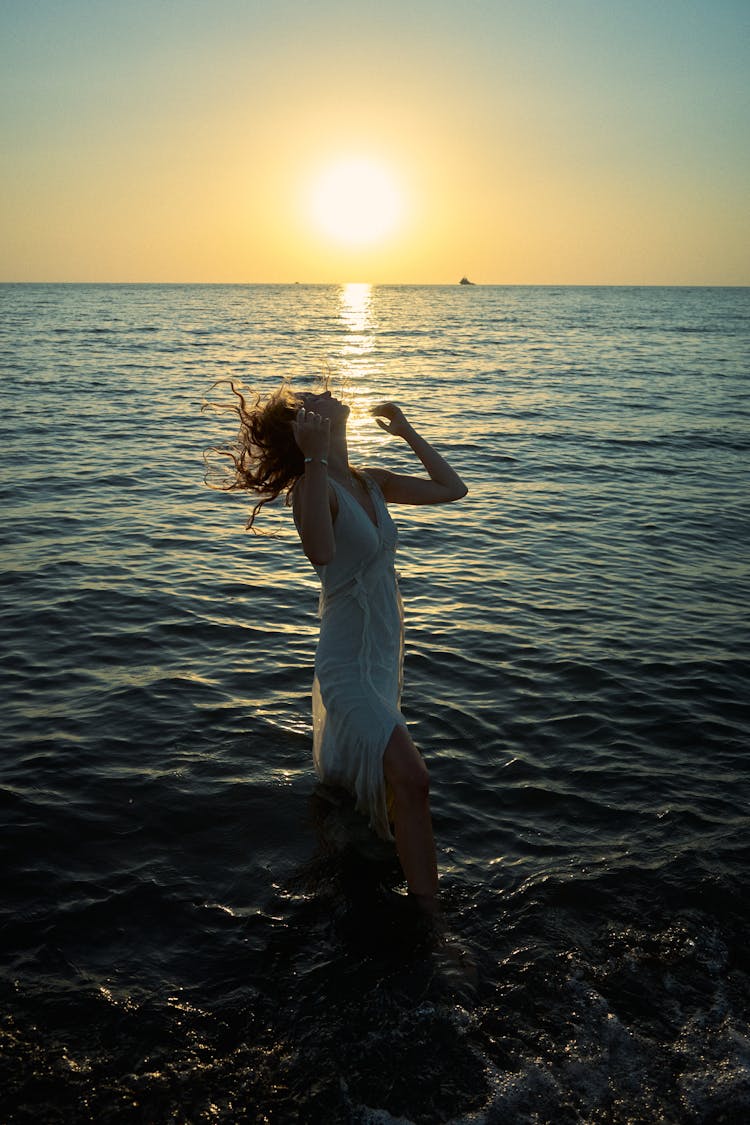 Woman Posing In Water At Sunrise