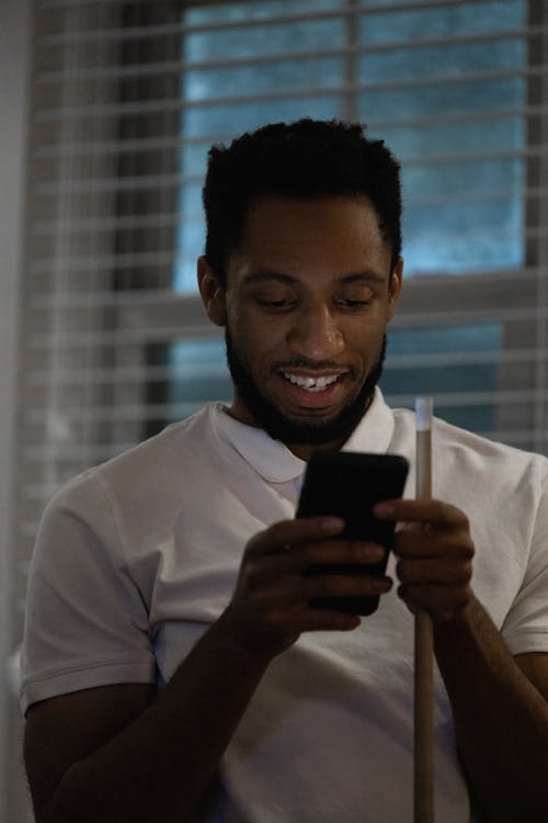 Close-Up Shot of a Man in White Polo Shirt Holding a Cellphone