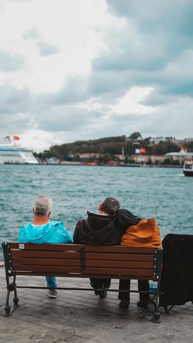 People Sitting On Bench And Looking At Sea