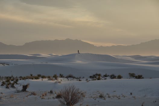 Lonely figure walking on the majestic White Sands dunes in New Mexico during sunset.