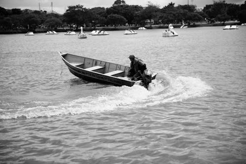 A Grayscale of a Man Riding a Boat in a Lake