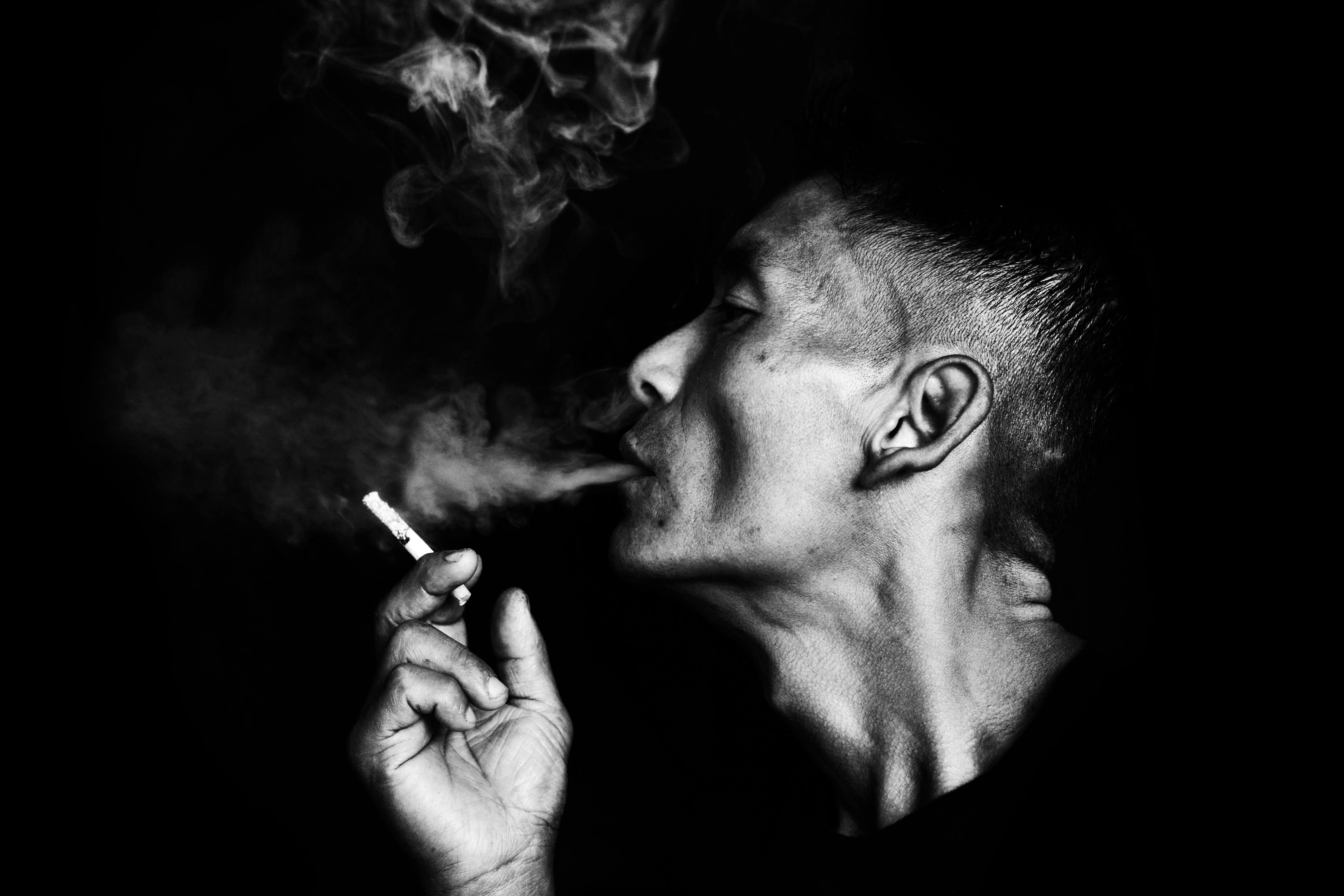 Dramatic black and white portrait of a man smoking, highlighting the smoke patterns.