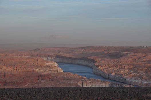 Panoramic view of the Colorado River meandering through the rocky Arizona canyon at sunset.