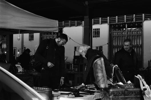 Black and white photo capturing a bustling market interaction in Florence, Italy.