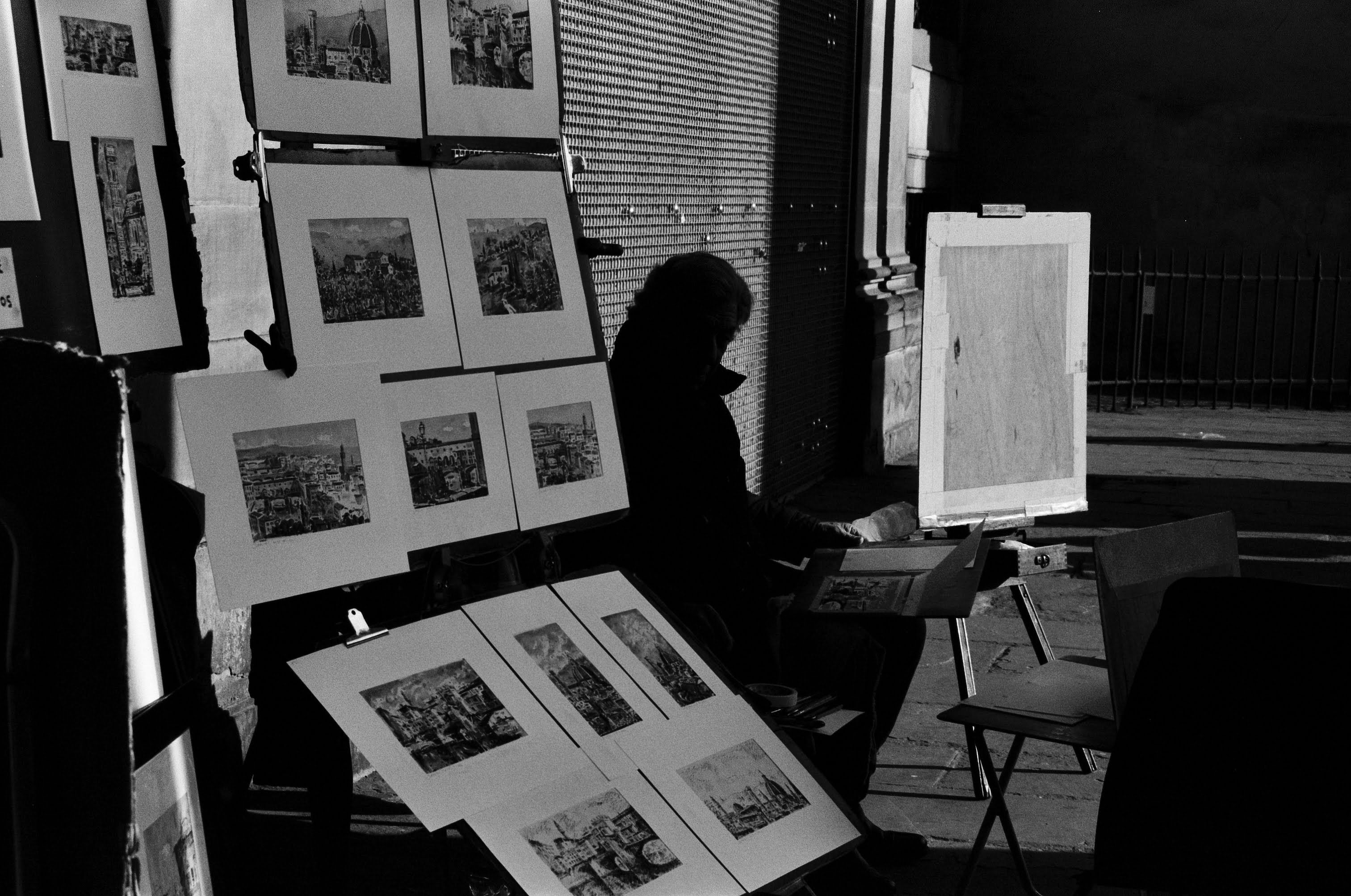 Black and white photo of a street artist with sketches in Florence, Italy.