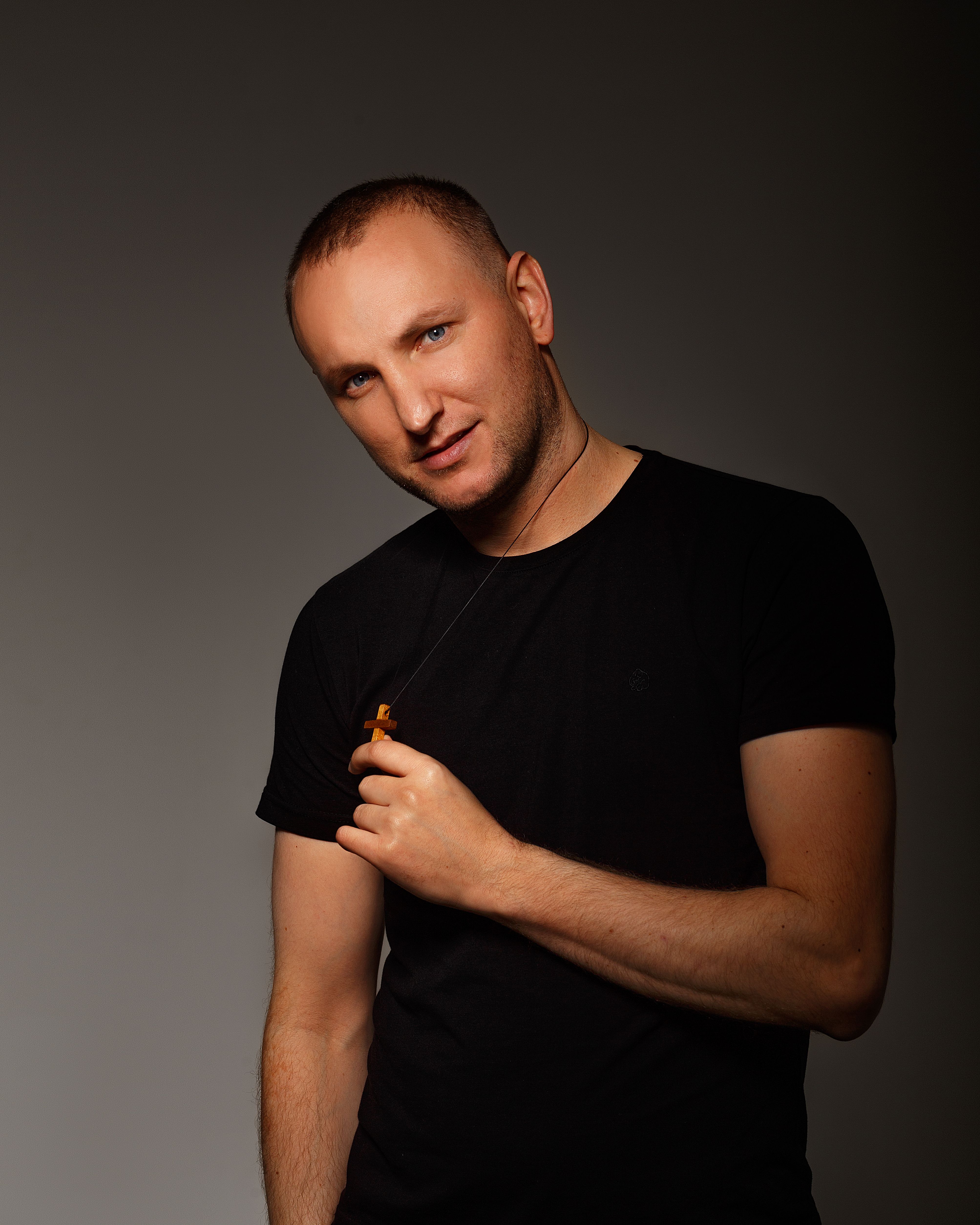 Close-up portrait of a caucasian man wearing a black shirt on a dark background.