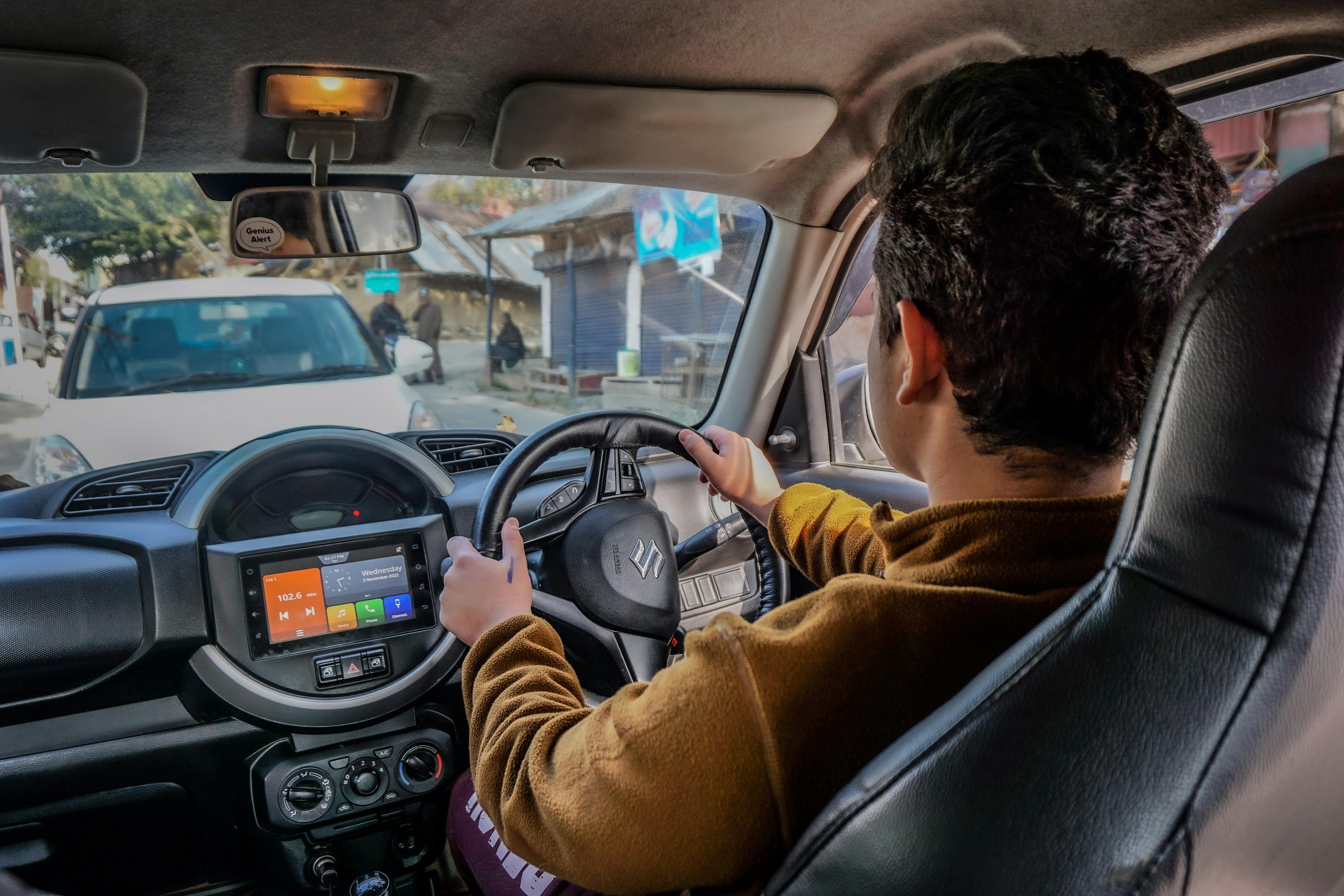 Close-up of a man driving a car on a scenic road in Baramulla, showcasing interior details.