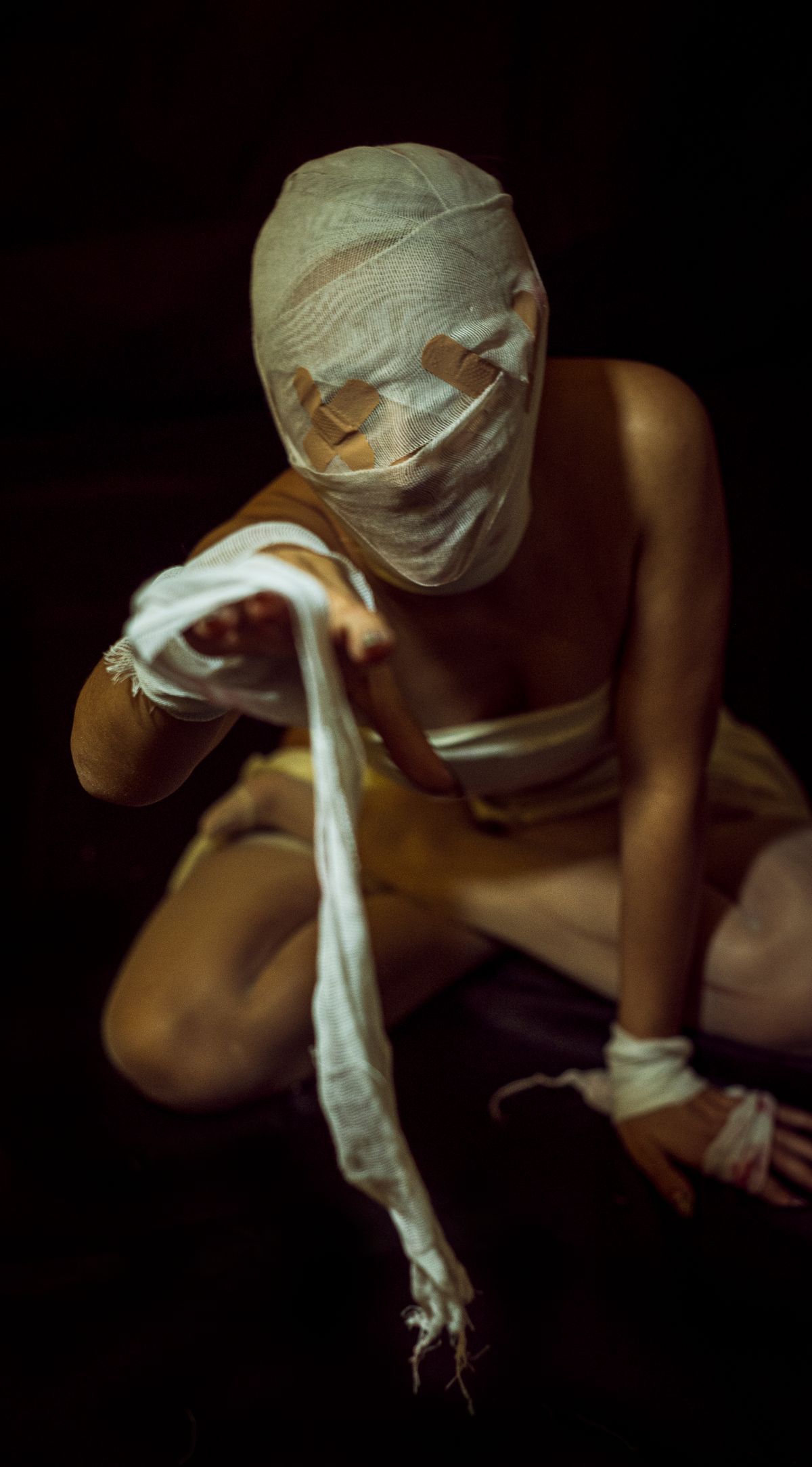 Adult wrapped in bandages like a mummy in a dimly lit setting for halloween costume ideas for adults