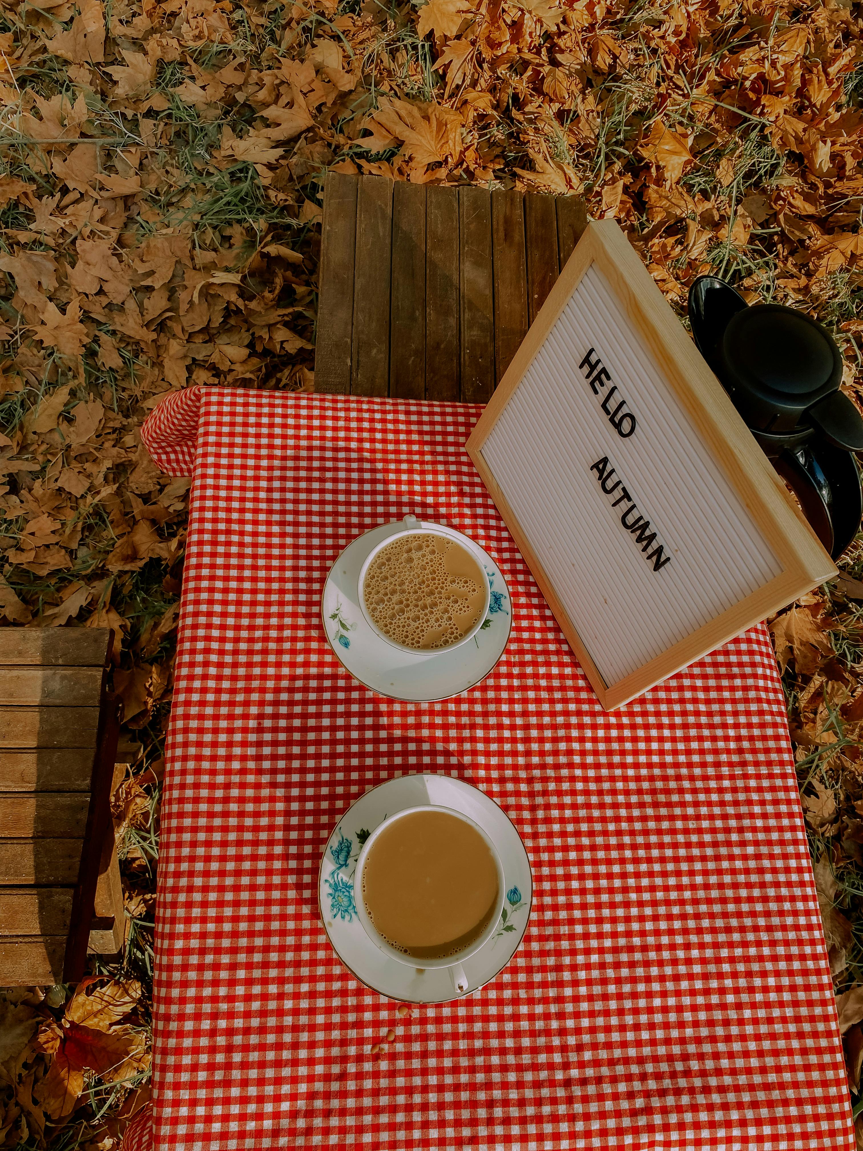 Cozy autumn outdoor cafe table with coffee cups and fallen leaves.