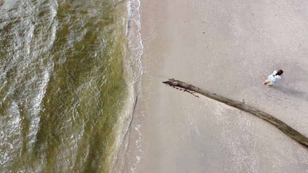 Drone shot of a sandy beach in Trinidad with waves and a person walking by driftwood.