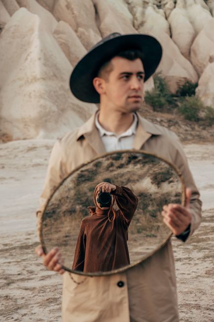 Creative outdoor portrait with a man holding a mirror showing a reflection of a photographer.