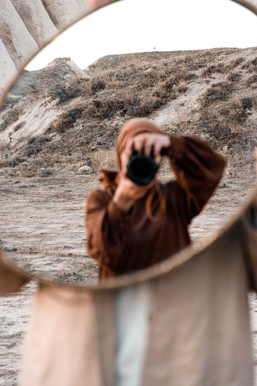 Free Blurry mirror reflection of a person capturing a scenic view outdoors with a camera Stock Photo