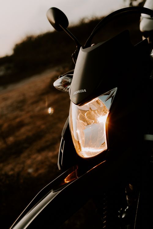 Free Artistic capture of a motorcycle headlight with glowing sunlight reflections. Stock Photo