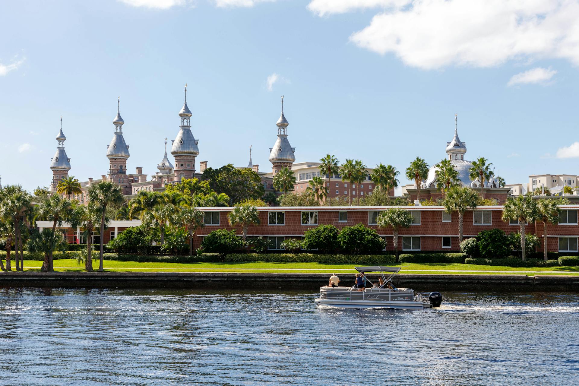 A beautiful view of the University of Tampa's historic architecture across the Hillsborough River with a boat in the foreground.