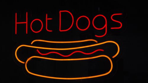 Free Bright neon sign showcasing hot dogs, capturing the essence of street food and modern fast food culture. Stock Photo