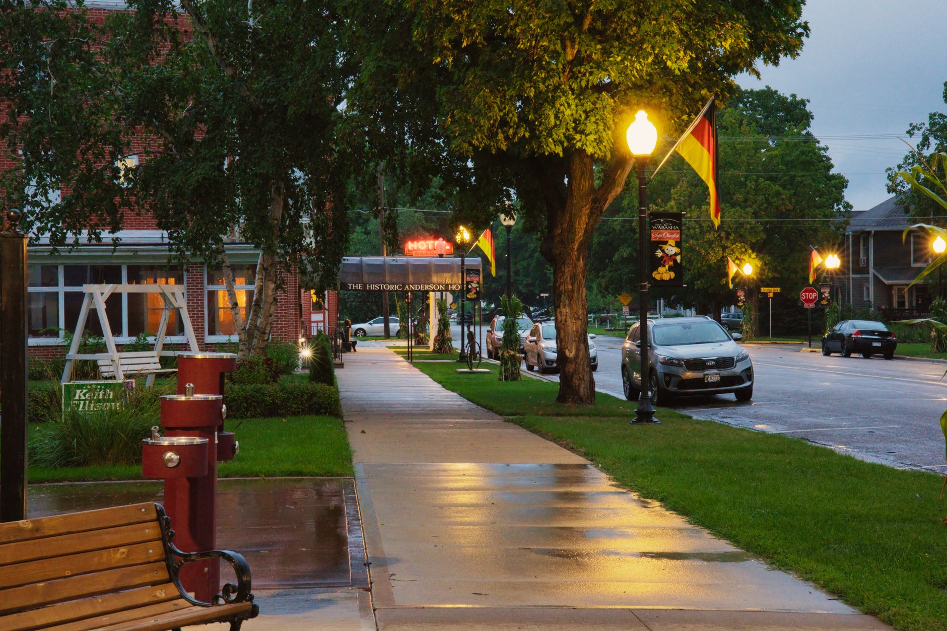 A serene evening street scene in Wabasha, MN, showcasing lit lamps and a wet pathway.