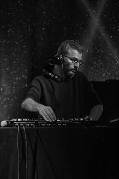 DJ engrossed in music performance at a live concert in a monochrome setting.