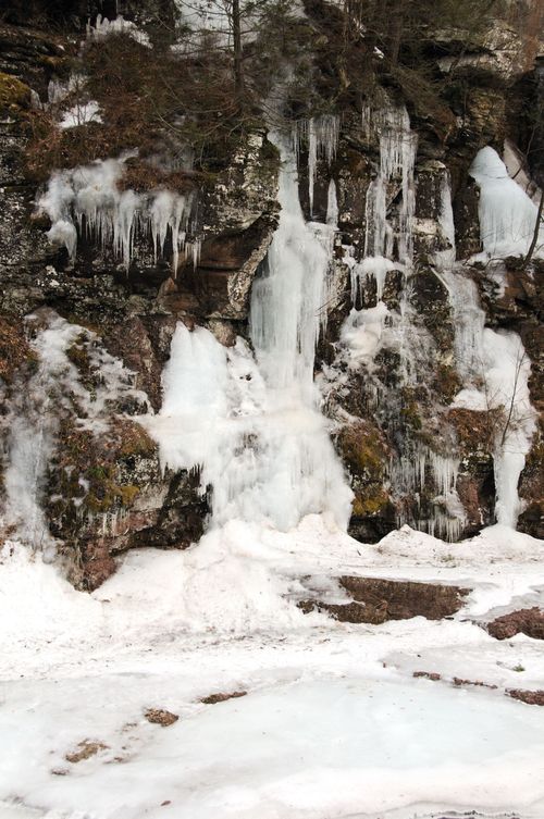 Free Scenic view of a frozen waterfall cascading down a rocky mountain face in winter. Stock Photo