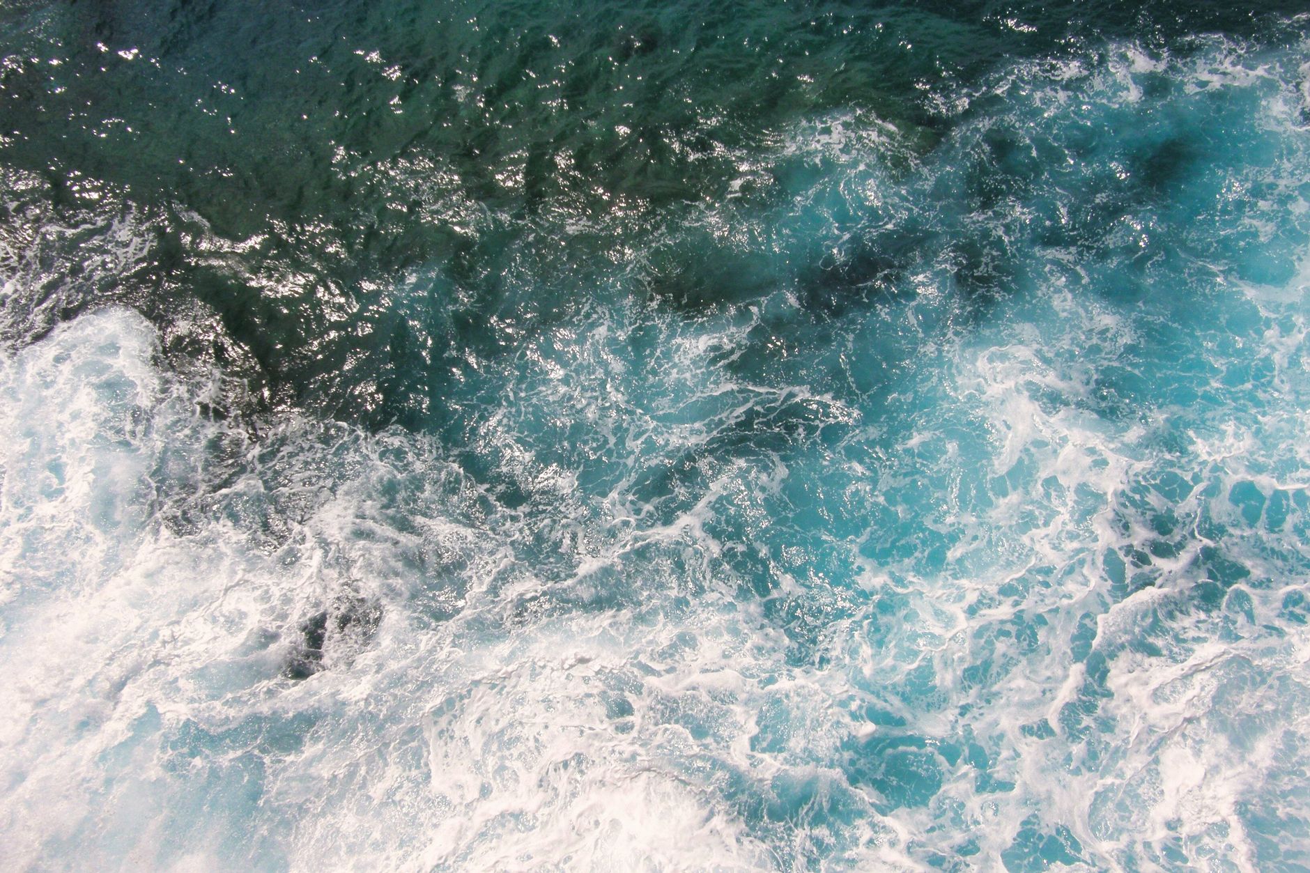 Captivadora toma aérea de olas rompiendo en agua clara del océano azul, mostrando la belleza de la naturaleza.