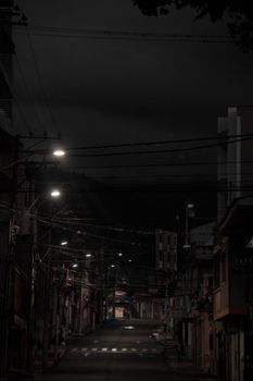 A quiet urban street illuminated by streetlights at night, showcasing a moody atmosphere.